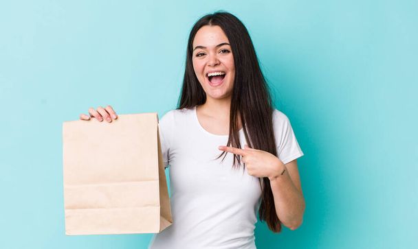 young adult woman looking excited and surprised pointing to the side. take away concept - Photo, image