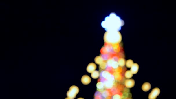 Gran árbol de Navidad de Año Nuevo decorado con luminosas guirnaldas multicolores e iluminación por la noche. Árbol de Navidad con luces intermitentes. Fondo borroso. Vacaciones de Año Nuevo y Navidad - Imágenes, Vídeo