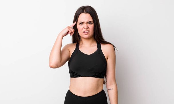 young adult woman feeling confused and puzzled, showing you are insane. fitness concept - Φωτογραφία, εικόνα