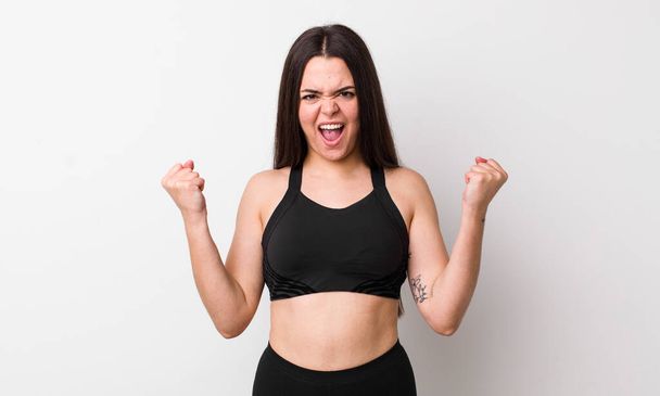 young adult woman shouting aggressively with an angry expression. fitness concept - Photo, Image