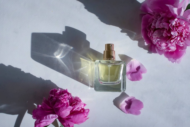 Perfume bottle, peony flower on a light background - Photo, image