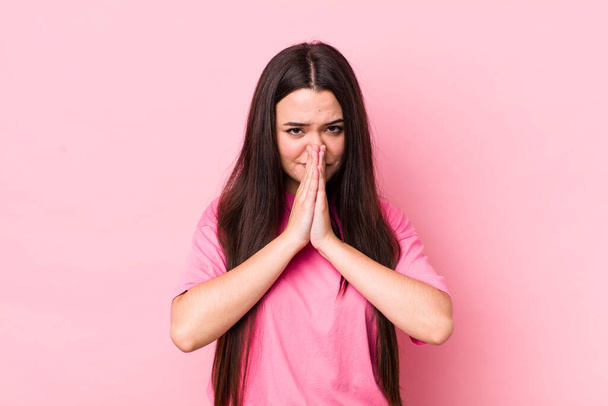 νεαρή ενήλικη γυναίκα αισθάνεται ανήσυχη, αισιόδοξη και θρήσκα, προσεύχεται πιστά με σφιγμένες παλάμες, ικετεύοντας συγχώρεση - Φωτογραφία, εικόνα