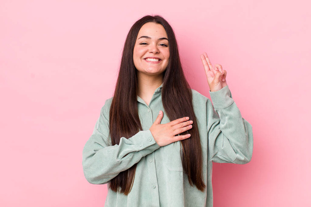 young adult woman looking happy, confident and trustworthy, smiling and showing victory sign, with a positive attitude - Photo, image