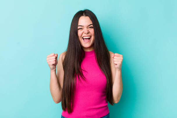 young adult woman feeling shocked, excited and happy, laughing and celebrating success, saying wow! - Foto, imagen