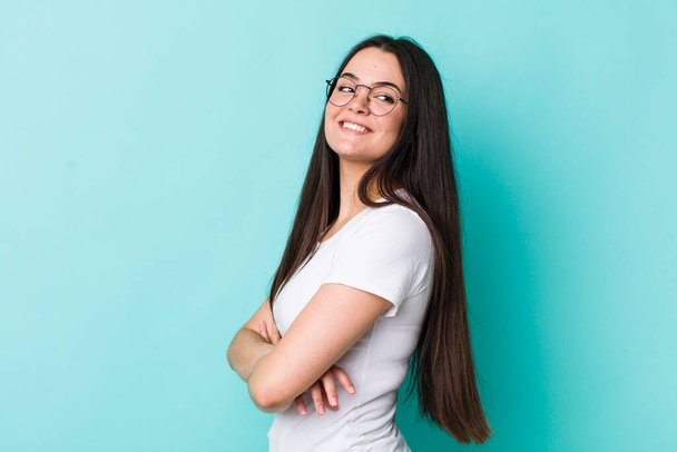 young adult woman smiling gleefully, feeling happy, satisfied and relaxed, with crossed arms and looking to the side - Foto, Imagen