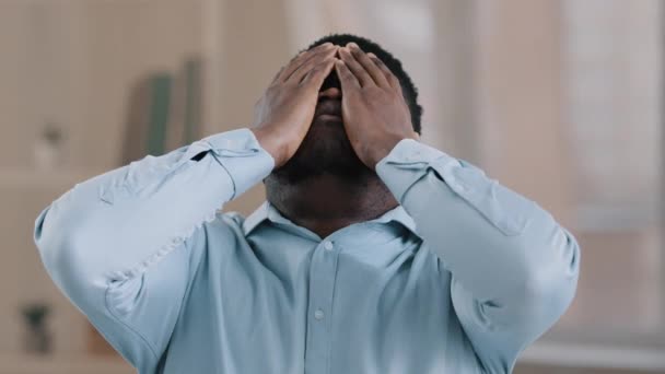 Muotokuva järkyttynyt turhautunut afrikkalainen amerikkalainen mies laittaa kädet otsaan väsynyt hukkua nuori liikemies miespuolinen työntekijä pettynyt menettää ongelma epäonnistuminen on päänsärky kärsivät migreeni tuntuu hermostunut - Materiaali, video
