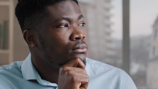 思考深刻な若いアフリカ系アメリカ人男性疑わしい男の夢の労働者ビジネスマン手で顎に座る自宅のオフィスで深い考えパズルを生成する新しいアイデアは難しい決定を下す - 映像、動画