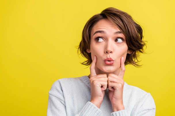 Photo of excited lady finger cheek look empty space open mouth wear blue sweater isolated yellow color background. - 写真・画像
