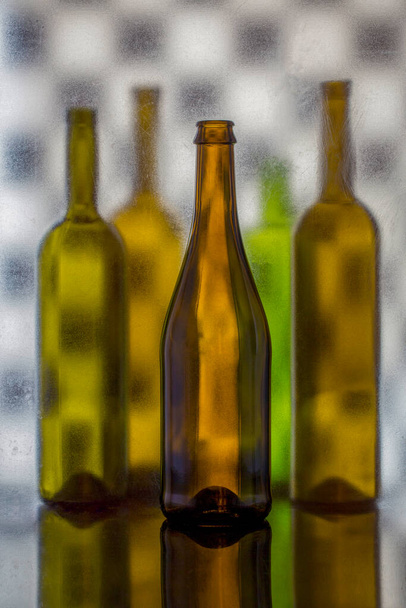 Натюрморт с цветными стеклянными бутылками на размытом фоне - Фото, изображение