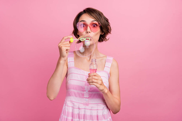 Photo of young girl amazed surprised blow big soap bubbles eyewear isolated over pink color background. - Φωτογραφία, εικόνα