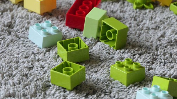 Meng van kleurrijke stukken Lego zittend op een mat binnen - Foto, afbeelding