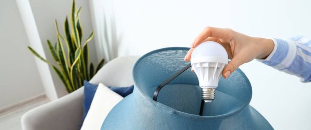 Woman changing light bulb of standard lamp at home - Photo, Image