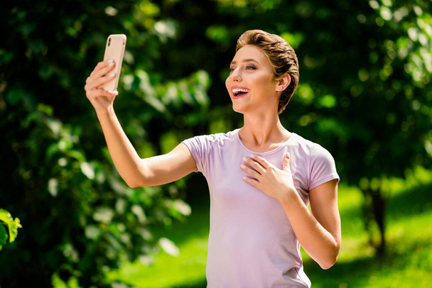 Portrait of attractive cheerful girl spending time on fresh air taking making selfie recording video outdoors. - 写真・画像