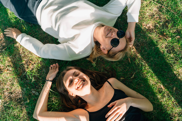Top view of mature mother and daughter lay on the grass on sunny summer day. High quality photo - 写真・画像