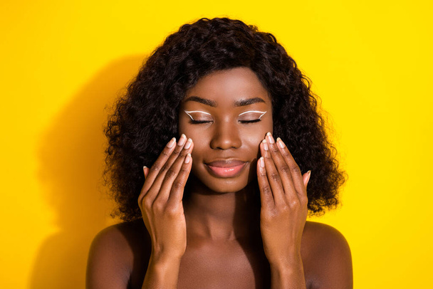 Photo of young beautiful lovely dreamy afro girl cleansing cheeks wash face apply cream isolated on yellow color background. - Fotografie, Obrázek