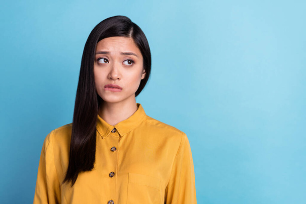 Photo of young attractive asian girl unhappy upset worried nervous bite lips fail look empty space isolated over blue color background. - Φωτογραφία, εικόνα