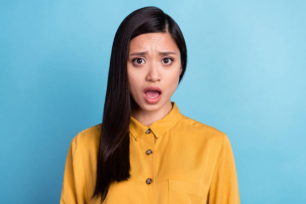 Fénykép ijesztő Y-generációs barna hölgy nyitott száj kopás sárga ing elszigetelt kék színű háttér. - Fotó, kép