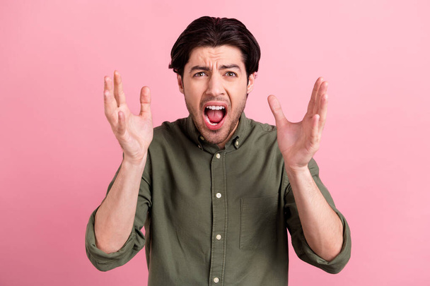 Photo of crazy guy afraid mood raise hands scream open mouth wear khaki shirt isolated pink color background. - Foto, immagini