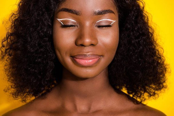 Photo of young happy lovely dreamy smiling afro girl wear no clothes with closed eyes isolated on yellow color background. - Fotografie, Obrázek