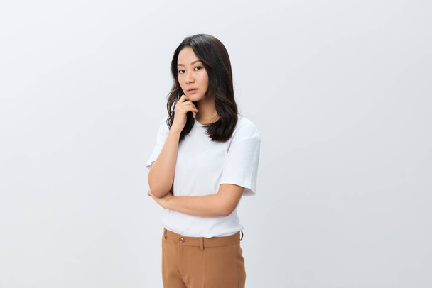 Attraktive süße koreanische Asiatin in weißem Basic-T-Shirt blickt isoliert in die Kamera, die auf weißem Studiohintergrund posiert. Das beste Angebot für Werbung. Menschen Lifestyle-Konzept. Kopierraum - Foto, Bild