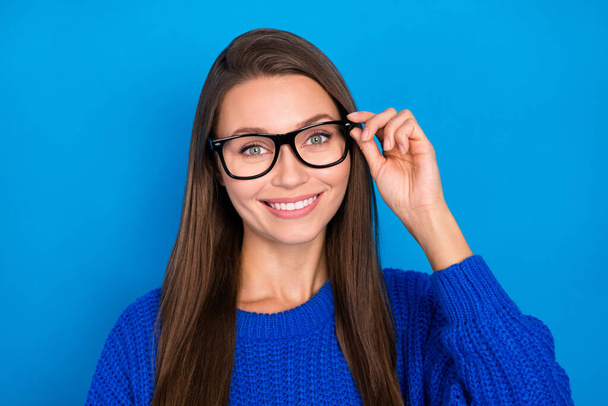 Portrait of attractive cheery experienced brown-haired girl learner touching specs isolated over bright blue color background. - Photo, image
