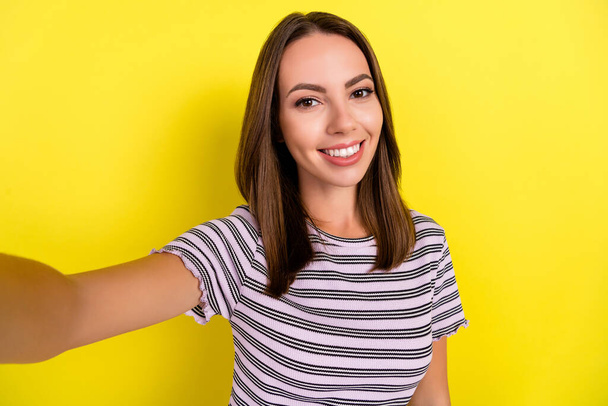 Photo of optimistic millennial brunette lady do selfie wear white t-shirt isolated on yellow background. - Fotografie, Obrázek