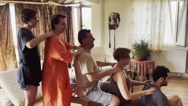 Los miembros de la familia se turnan para darse un masaje en el hombro en la sala de estar de la casa.. - Metraje, vídeo