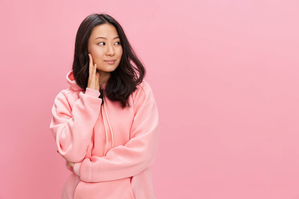 Awesome lovely cheerful happy Asian student young lady in pink hoodie sweatshirt folds hands posing isolated on over pink studio background. Good offer. Fashion New Collection concept - Photo, Image