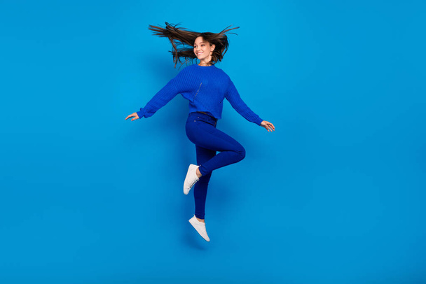Повнометражний вигляд на тіло привабливої веселої безтурботної дівчини, яка стрибає в дурі ізольовано на яскраво-синьому кольоровому фоні
. - Фото, зображення