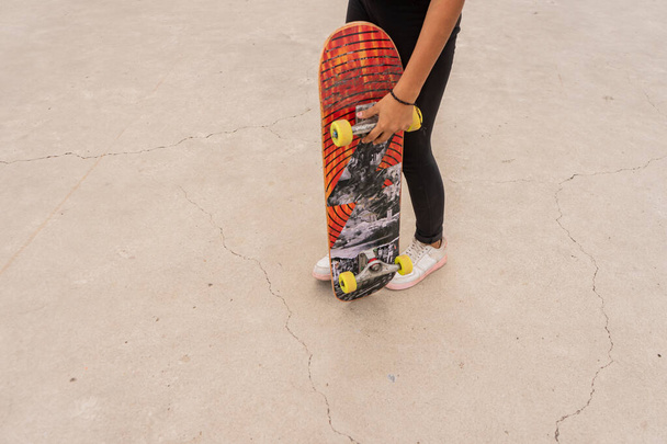 Unrecognizable latina teenage female skater holding a board about to do stunts in Managua Nicaragua - Фото, изображение