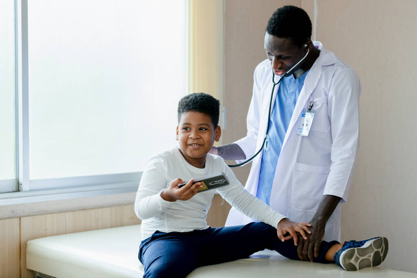 Afro-Amerikaanse medische mannelijke arts checkup diagnose kind jongen patiënt. Gezondheidszorgconcept. - Foto, afbeelding