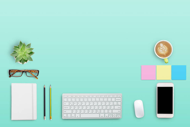 Moderner Arbeitsplatz von oben mit Kaffeetasse und Laptop, Notebook, Brille, Smartphone auf grünem Tischhintergrund. Flache Verlegestile. - Foto, Bild