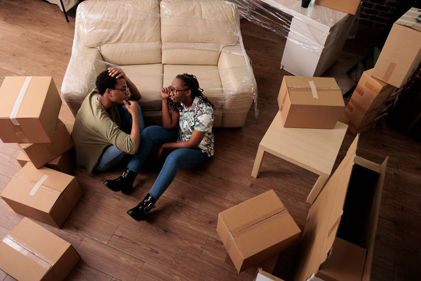 Семейные партнеры по жизни отдыхают вместе на полу в гостиной, обсуждают украшения и будущую семью. Получение удовольствия от переезда и перерыв после переезда, достижение взаимоотношений. Вид сверху. - Фото, изображение
