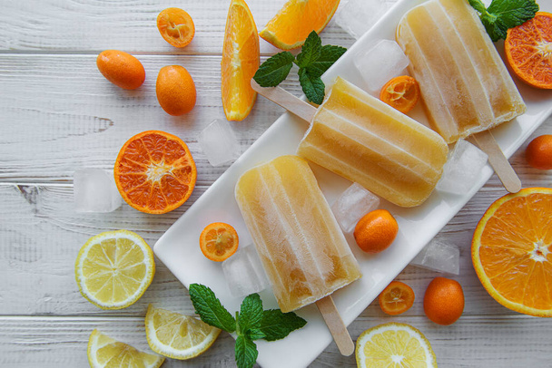 Fruit orange ice popsicle, ice cubes and slices of citrus fruits.  - Photo, Image