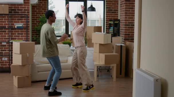 Cheerful couple dancing in new apartment celebrating relocation, having fun after moving in together. Feeling positive and doing funky dance moves, enjoying rented family property. - Footage, Video