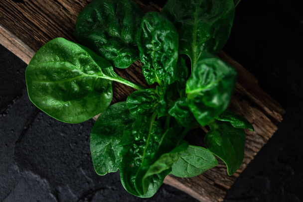 large spinach, a plant of the Amaranth family, on a wooden plate against a dark background - Fotografie, Obrázek