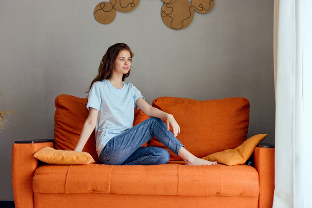 Улыбающаяся женщина на диване отдыхает весело Комфорт квартиры. Высокое качество фото - Фото, изображение