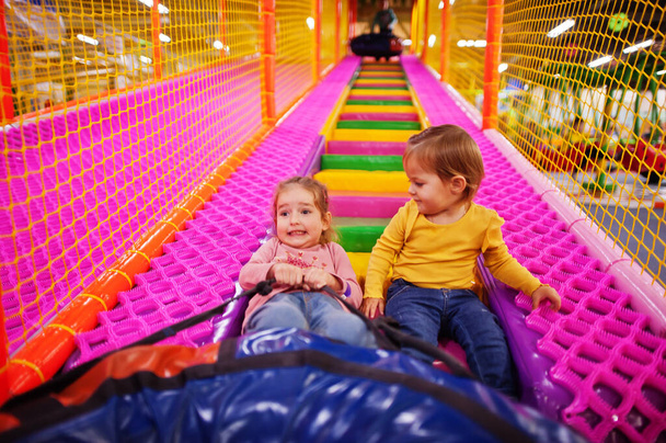 Two sisters sitting in tubing donuts enjoying slides in fun children center. - Photo, image
