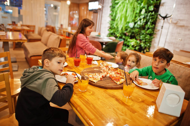 Mother with four childrens eat pizza in pizzeria.  - Fotó, kép