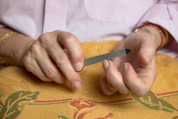 Female manicure. Woman's hands with a file, filing her nails - Photo, Image