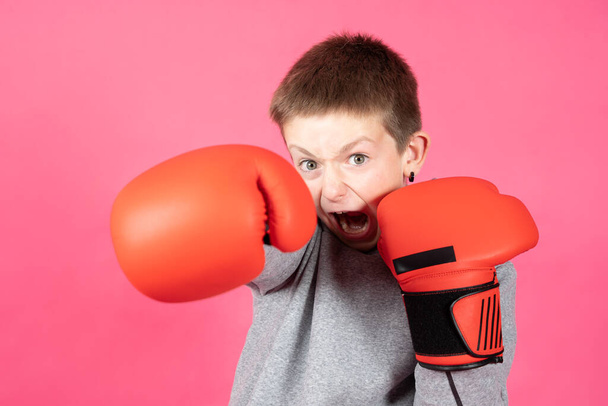 Aggressive teenager boy giving a punch and looking at camera isolated on pink background. Bullying defense concept. - Фото, зображення