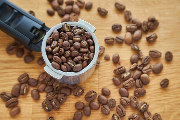 Кофейные зерна в кофейном роге на фоне кофейных зерен - Фото, изображение