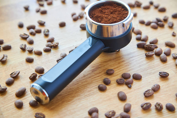 Kávovar roh s přízemní kávou na dřevěném pozadí a kávová zrna - Fotografie, Obrázek