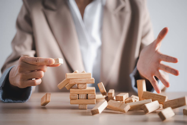 wooden block tower collapse with woman hand, business strategy concept - Fotoğraf, Görsel