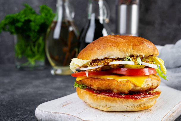 Tasty chicken burger with lettuce, cheese, tomato and pickle. Fast food sandwich with chicken cutlet - Фото, зображення