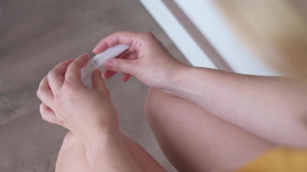 Onherkenbare vrouw die zwangerschapstest doet in de badkamer. Meisje met een positieve zwangerschapstest met twee regels. Close-up shot van de zwangerschapstest kit in handen. - Video