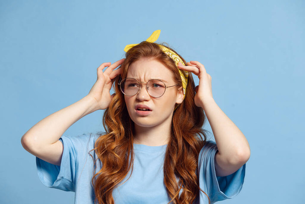 Scared young redhead girl, student posing isolated on blue studio background. Human emotions, facial expression concept. Trendy colors. Youth culture, sales, discount. Copy space for ad - Foto, Imagem
