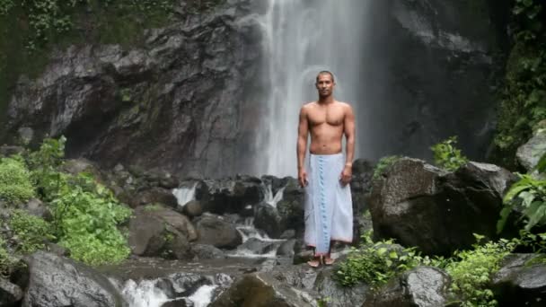 Mans standing under waterfall in the tropics - Séquence, vidéo