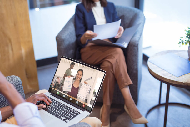 Smiling asian businesswoman showing reports to african american male colleague on video call. unaltered, business, wireless technology, data, working, teamwork and office concept. - Photo, image