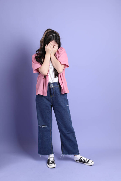 The cute young Asian girl with casual clothes standing on the purple background. - Φωτογραφία, εικόνα